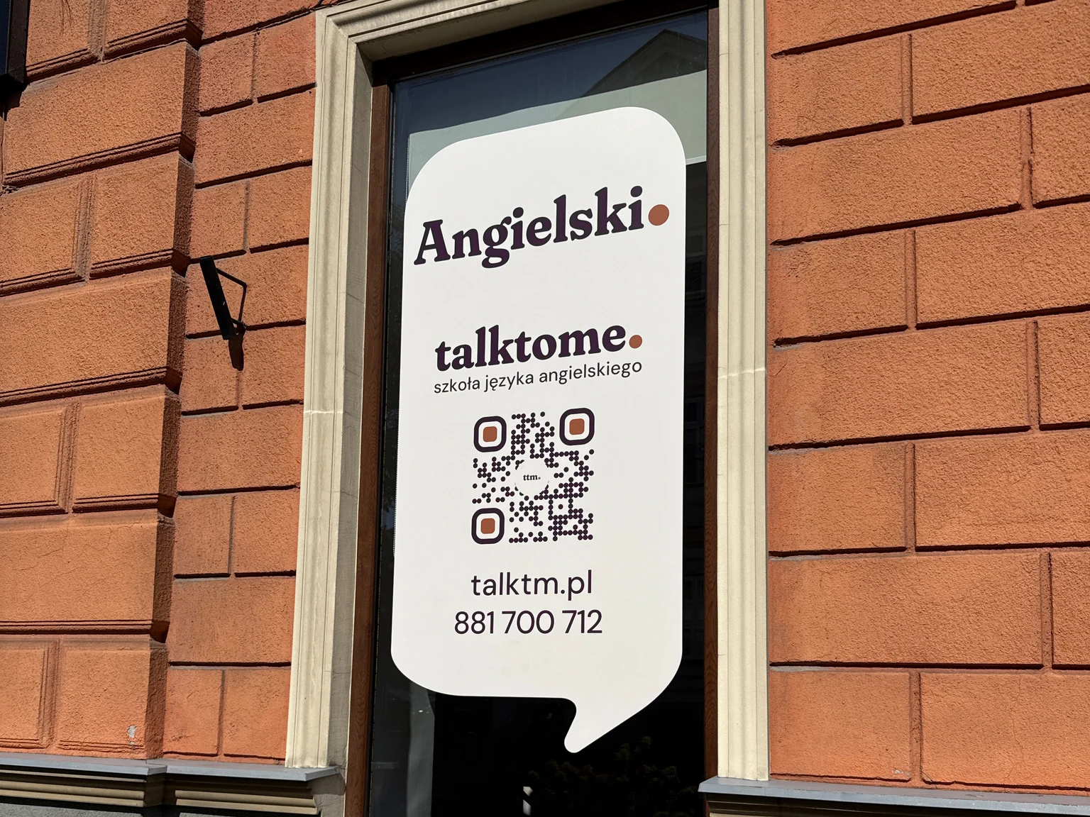 Szyld okienny talktome. szkoła języka angielskiego z kodem QR na zabytkowej kamienicy